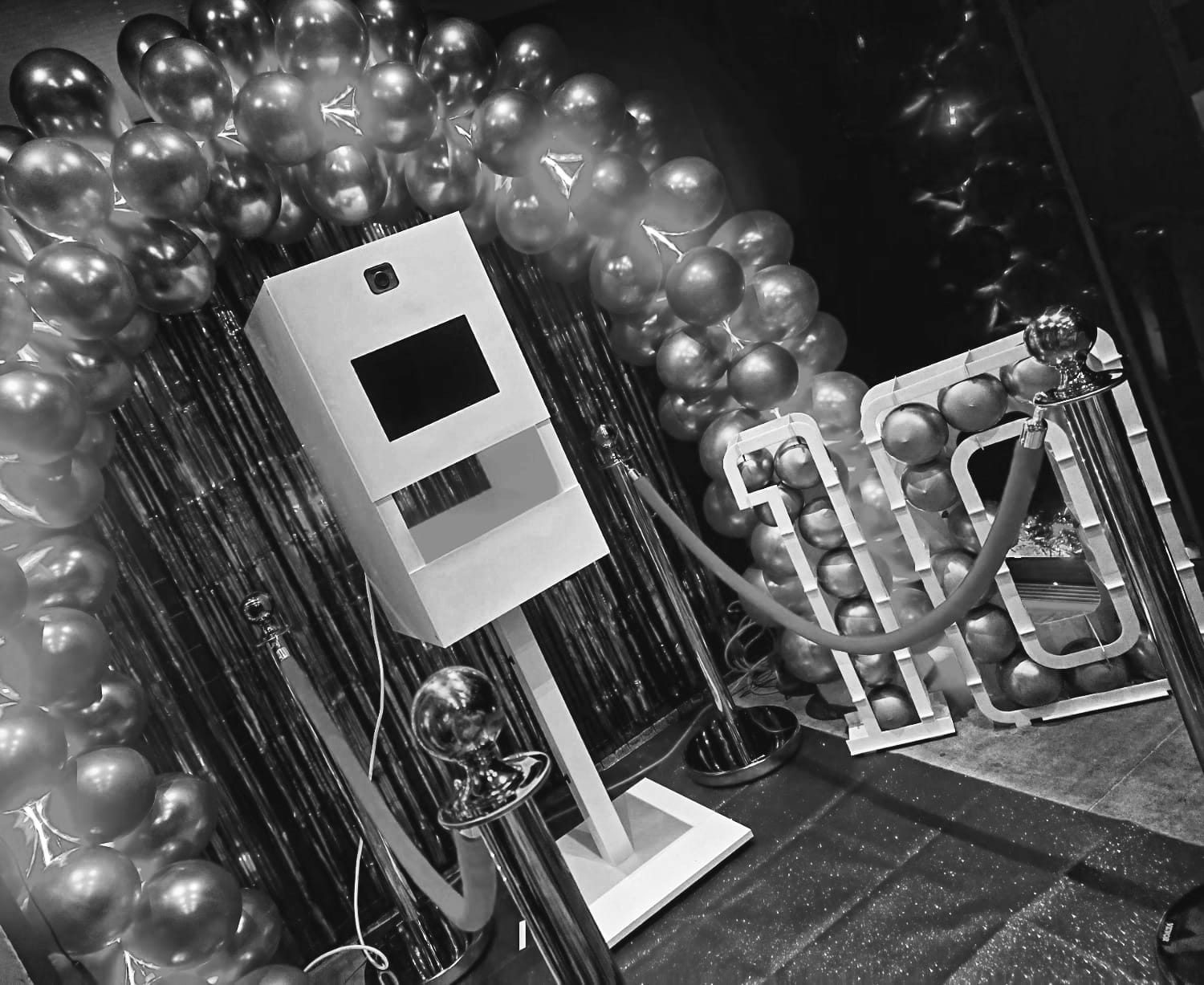 Fotobooth met feestelijke ballonnen en rode loper in een feestelijke setting.