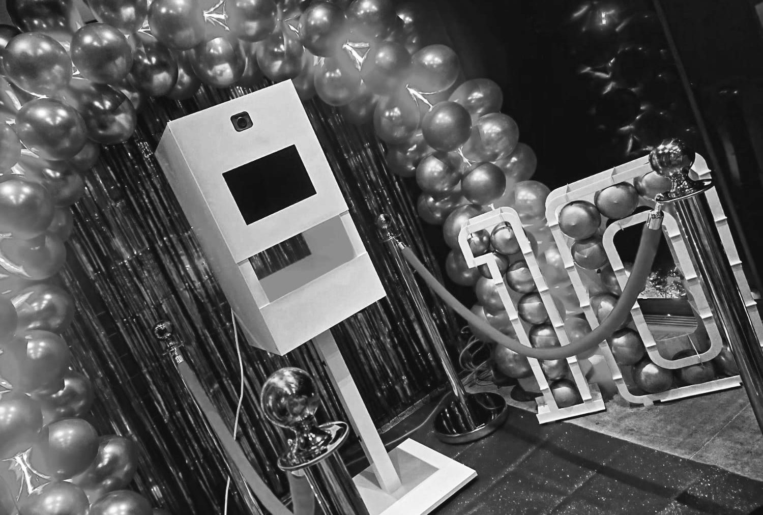 Fotobooth met feestelijke ballonnen en rode loper in een feestelijke setting.